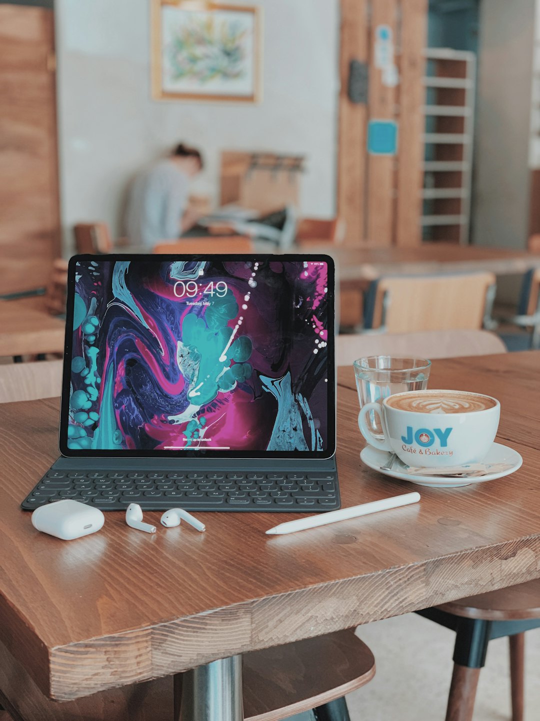 Tablet dan latte di atas meja kayu kafe.