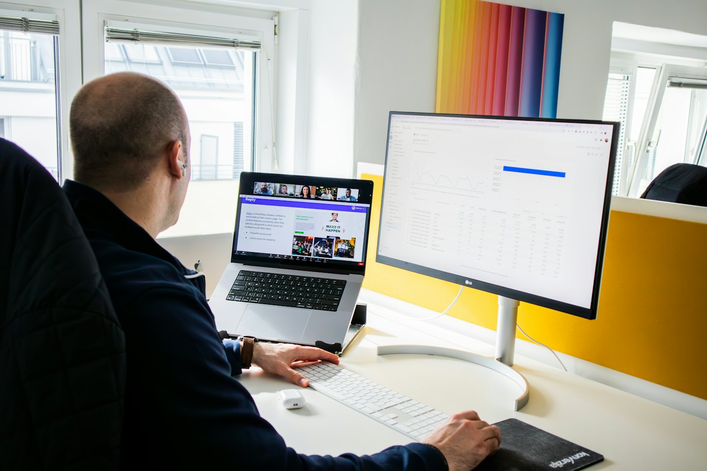 Pria bekerja di laptop dan monitor di kantor modern.