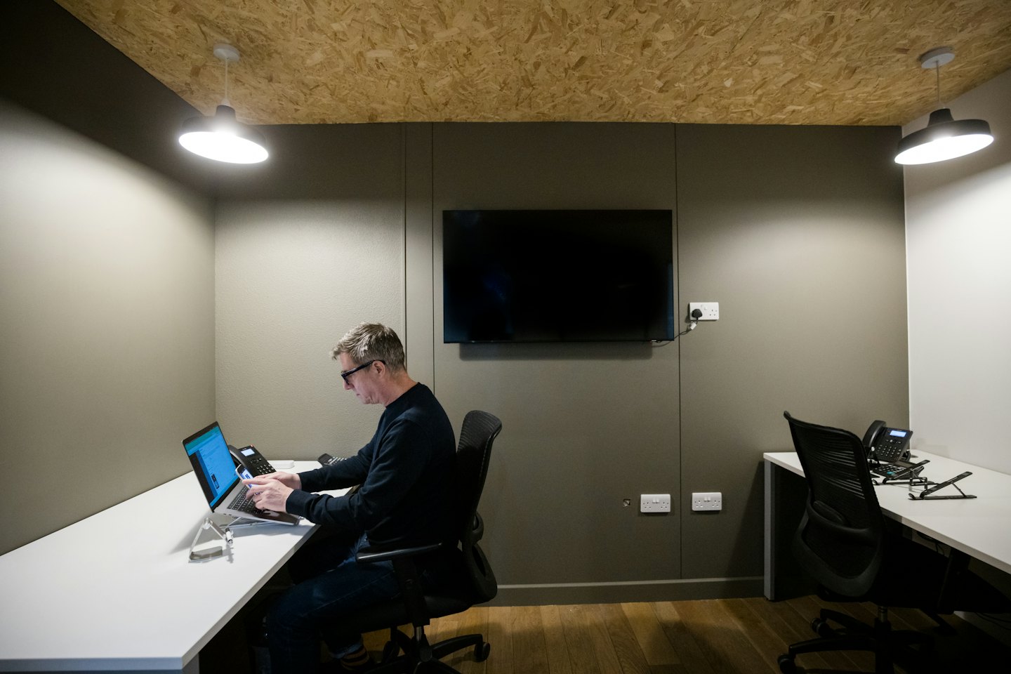 Pria bekerja di laptop di meja putih di kantor modern.